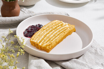 Medovik honey cake slice with berry jam, bright sunlight, overhead minimal composition