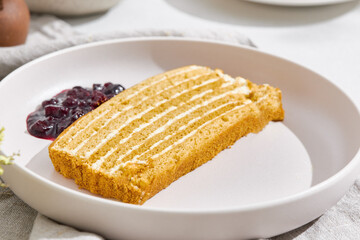 Medovik honey cake slice, bright summer lighting, minimal overhead composition, paired with berry jam