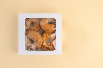 Bagels in a white box on a beige background, top view