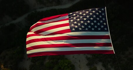 Majestic, orange glow on massive American flag hanging in canyon - high drone shot - Powered by Adobe