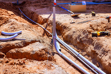 Workers install plumbing pipes in trench at construction site under works day