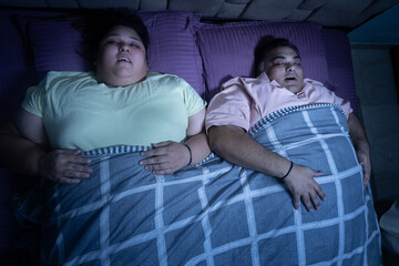 Overweight indian couple sleeping well in bed. Plus size husband wife resting together.