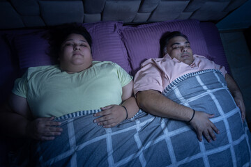 Overweight indian couple sleeping well in bed. Plus size husband wife resting together.