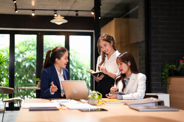 Focused female intern listening to senior  business woman mentor teacher explaining online strategy looking at laptop computer teach trainee training new worker learning new skill at workplace.