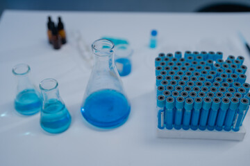 Laboratory setting featuring blue liquid in various glassware and a rack of test tubes, illustrating scientific research and experimentation in a controlled environment