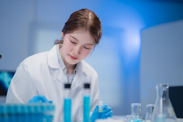 Fototapeta premium Focused young scientist in a laboratory setting, conducting experiments with test tubes and beakers. Wearing a lab coat and gloves, she demonstrates precision and concentration in her work