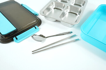 Plastic and stainless lunch box, which is black and blue in color. n white background, food...
