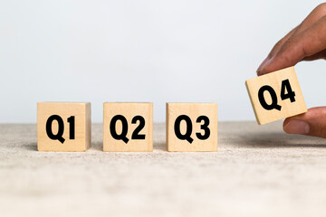 male hand put wooden cubes with q1, q2, q3, q4 symbol isolated on white background. concept of...