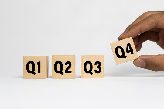 male hand put wooden cubes with q1, q2, q3, q4 symbol isolated on white background. concept of quarterly report annual