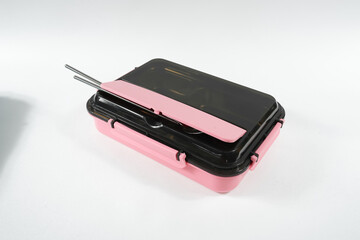 Plastic and stainless lunch box, which is black and pink in color. n white background, food...