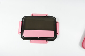 Plastic and stainless lunch box, which is black and pink in color. n white background, food...