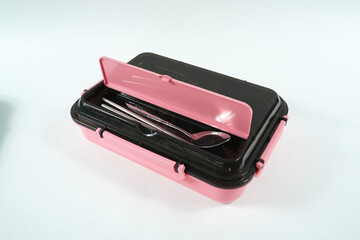 Plastic and stainless lunch box, which is black and pink in color. n white background, food...
