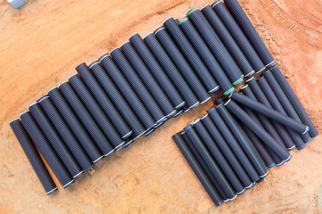 Black rubber pipes meticulously lined up at construction site, ready for installation after...
