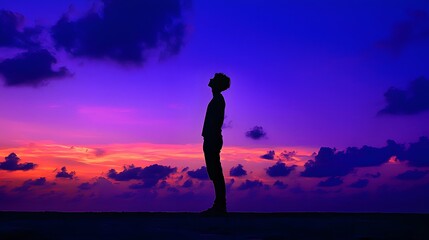 Silhouette of a young man against a vibrant sunset sky.