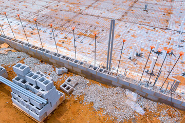 Heavy construction activity underway with concrete blocks steel bars being prepared for building...
