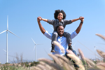African american parents take their children to visit and admire renewable energy wind turbines....