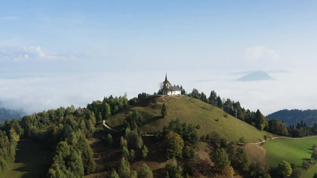 St. Thomas Church (Cerkev Sveti Tomaž) In The Hills Near The Town Of Skofja Loka, Slovenia. Aerial Wide Shot