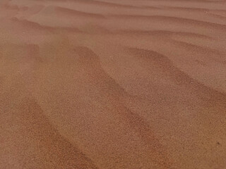 Endless red sand dunes under a clear blue sky in a desert landscape. Nature's raw beauty, peaceful and untouched by humans.

