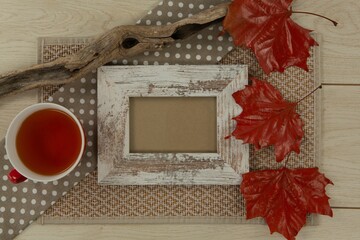 Photo frame, lemon tea and red leaves on wooden table