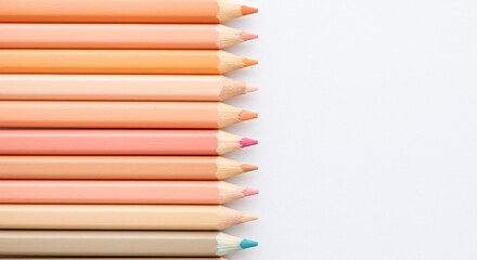 Fototapeta premium Pastel colored pencils arranged in a row against a white background create a soft visual