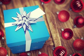 Vector graphic showcasing blue gift box with white ribbon, silver bow, red baubles on wood tabletop