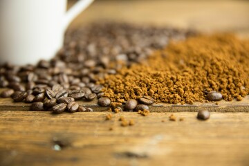 Coffee beans are spilling beside ground coffee on rustic table and blurred mug in flat design © vectorfusionart