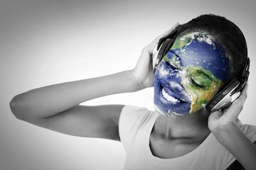 Woman is wearing over-ear headphones and showing world map face paint in studio portrait