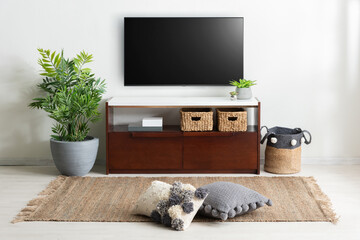 Mid-century inspired dark wood TV console with white top and rattan baskets, styled with floor...