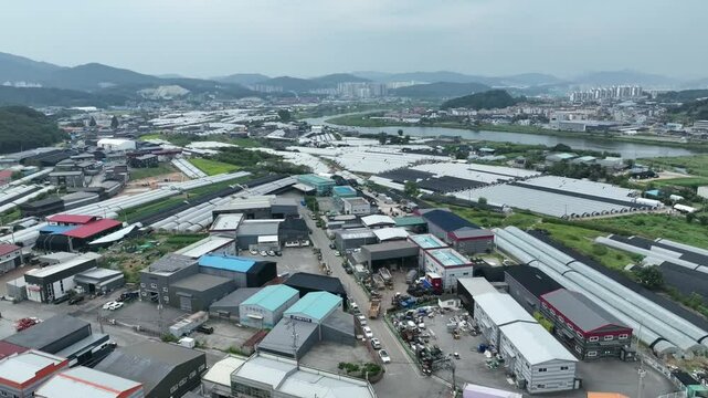 Yongin, Korea &ndash; July 9, 2025: Drone view of greenhouse complex and industrial area near river. This content is for editorial use only. No model or property release is required.This content is for edi
