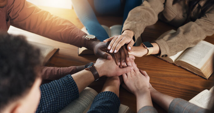 Stack of hands, bible and people by table for unity, solidarity and support at religion study. Trust, top view and prayer group with partnership and collaboration with holy book for worship community