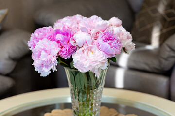 Beautiful peonies in glass vase on table.