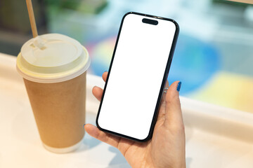 Woman Hand Holding Smartphone with Blank Screen and Coffee Cup. Ideal for app or website mockup....