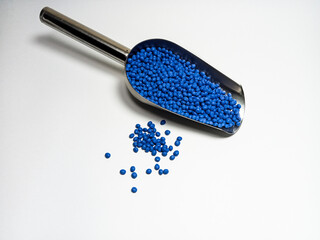 Blue plastic masterbatch, polymer carries colorful pigments with small scoops poured into a white background, suitable for product catalog design of industrial plastic manufacturing company profiles