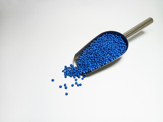 Blue plastic masterbatch, polymer carries colorful pigments with small scoops poured into a white background, suitable for product catalog design of industrial plastic manufacturing company profiles