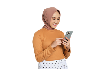 Cheerful young Muslim woman in hijab texting on smartphone while standing isolated on transparent background