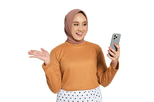 Happy Muslim woman in hijab waving hand while video calling on smartphone isolated on transparent background