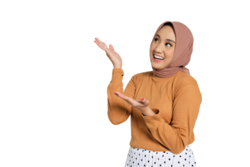 Smiling Muslim woman in hijab pointing upward with open hands while looking up isolated on transparent background