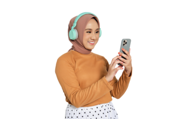 Muslim woman in hijab wearing headphones and using smartphone while smiling isolated on transparent background