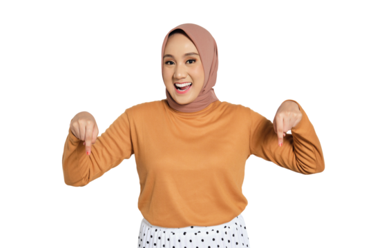 Cheerful woman wearing hijab smiling and pointing down with both hands isolated on transparent background