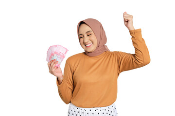 Happy young Muslim woman in hijab holding Indonesian rupiah money and celebrating success isolated...
