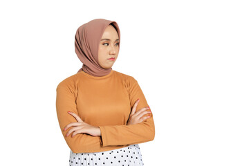 Unhappy young Muslim woman in hijab crossing arms and looking away with displeased expression...