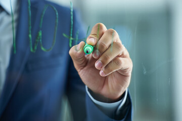 Hand writing on glass with a green marker wearing a blue business suit coat