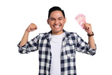 Happy young man in checkered shirt holding Indonesian rupiah money and celebrating success with clenched fist isolated on transparent background