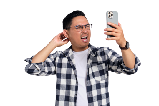 Confused young man wearing glasses scratching head and looking at smartphone screen with puzzled expression isolated on transparent background
