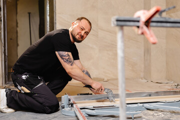 Construction Worker Cutting Ceramic Tile Using Tile Cutter in Bathroom