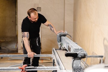 Construction worker cutting ceramic tiles using professional machine