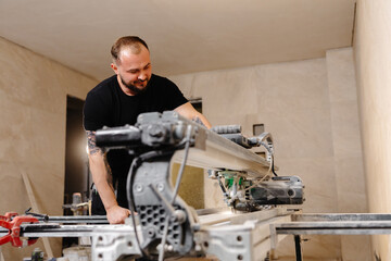 Construction worker cutting ceramic tiles using professional machine
