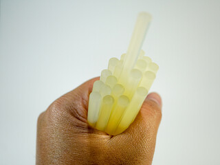 Close up shows hot melt adhesive sticks held by a hand against a light background ready for...