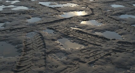Vast expanse of dark wet earth imprinted with varied tire tracks and scattered reflective puddles