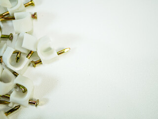 Cable clips with nails scattered across white surface ready to organize wires in home construction...